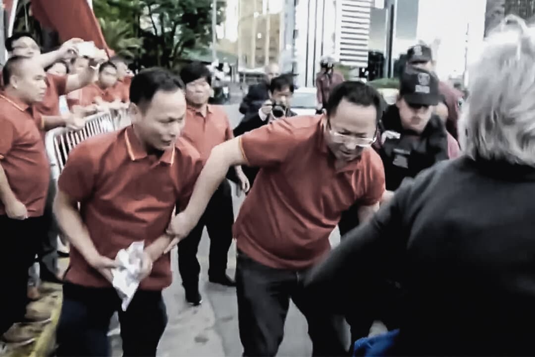Chinese Communist Party supporters grab and destroy pamphlets belonging to a Falun Gong practitioner, in Buenos Aires, Argentina, on Nov. 29, 2018, in a still from video. The local police arrested nine Falun Gong practitioners but let the attackers go. (Video provided to The Epoch Times)
