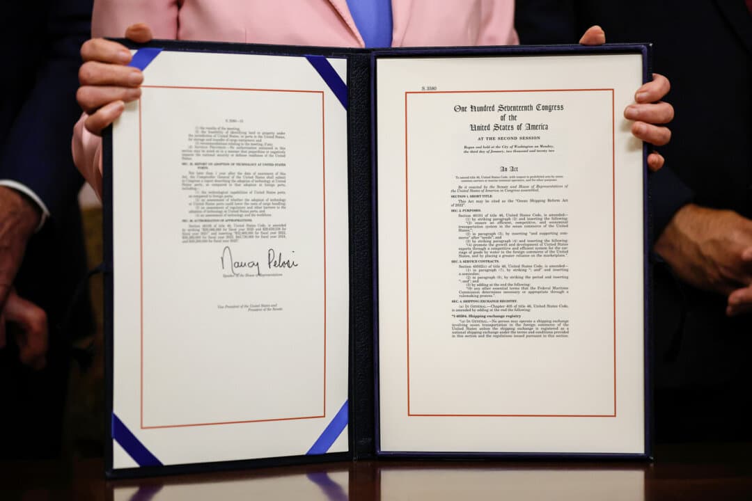 Then-Speaker of the House Nancy Pelosi (D-Calif.) holds the Ocean Shipping Reform Act while posing for photographs during the enrollment ceremony in her ceremonial office at the U.S. Capitol in Washington on June 14, 2022. Under the act, the Federal Maritime Commission was granted new authority to regulate ocean carrier practice. (Chip Somodevilla/Getty Images)