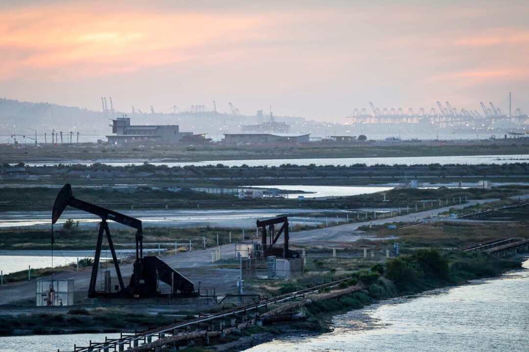 A pumpjack stands idle in the Huntington Beach oil field, with port cranes visible in the distance, in Huntington Beach, Calif., on April 23, 2026. America benefits not only from domestic supply, but also from substantial imports from Canada. (Mario Tama/Getty Images)