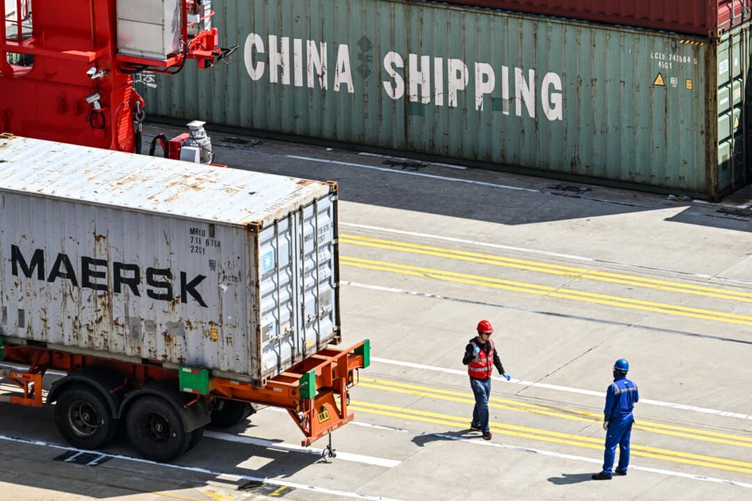 Workers stand next to a truck transporting a container at the Yangshan Deep-Water Port near Shanghai on June 3, 2025. (Hector Retamal/AFP via Getty Images)