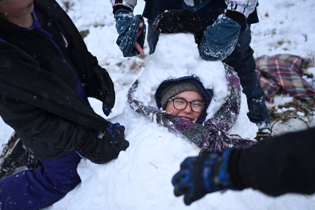 People enjoy the snowfall while playing in a snow pile during one of the largest May snowstorms in decades in Longmont, Colo., on May 6, 2026. The storm blanketed the Front Range amid the worst drought Colorado has seen since 1883. (Mark Makela/Getty Images)