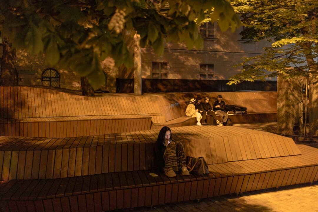 People sit on a wooden bench-terrace at Lithuanian Square amid the Russian invasion of Ukraine in downtown Kyiv, Ukraine, on May 11, 2026. (Roman Pilipey/AFP via Getty Images)