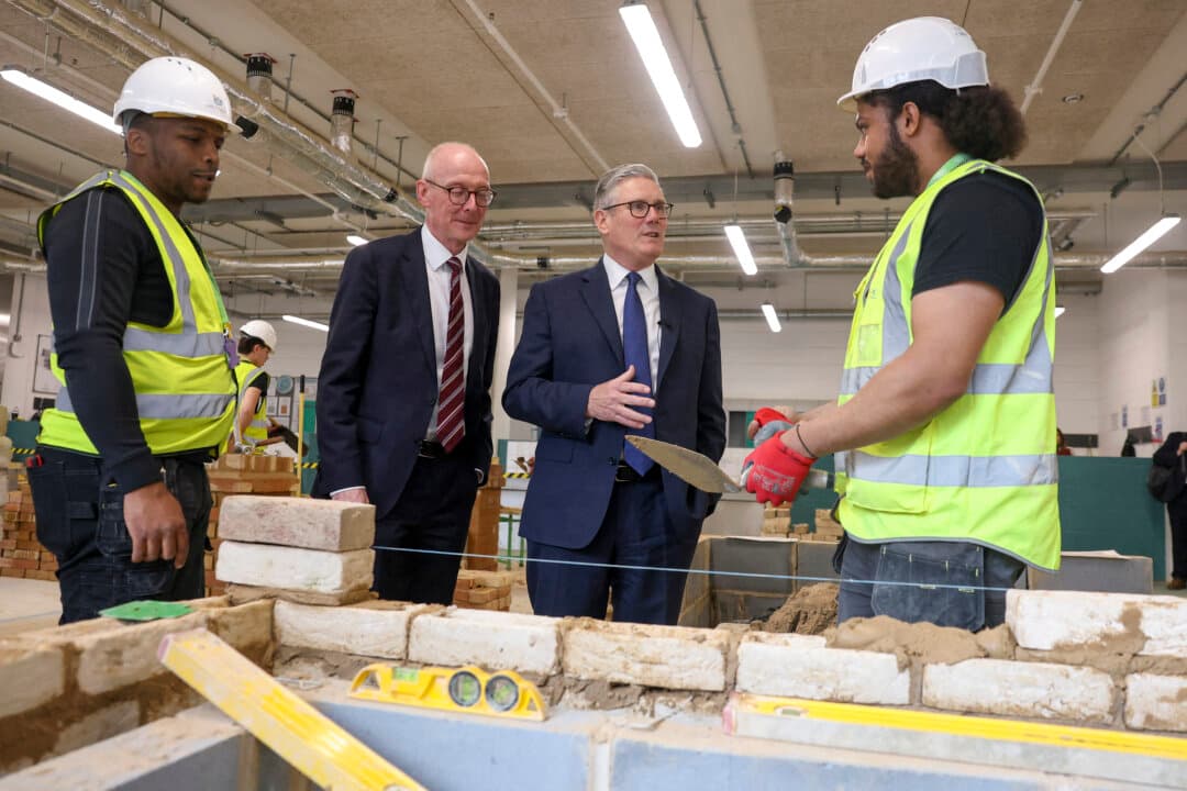 Britain's Prime Minister Keir Starmer (2nd R) and Pensions Secretary Pat McFadden (2nd L) meet construction apprentices during a visit to London South Bank Technical College on May 12, 2026. More than 100 Labor MPs have signed a statement in a show of support for Prime Minister Keir Starmer, who is under pressure to step down after devastating elections. (Toby Melville/Pool/AFP via Getty Images)