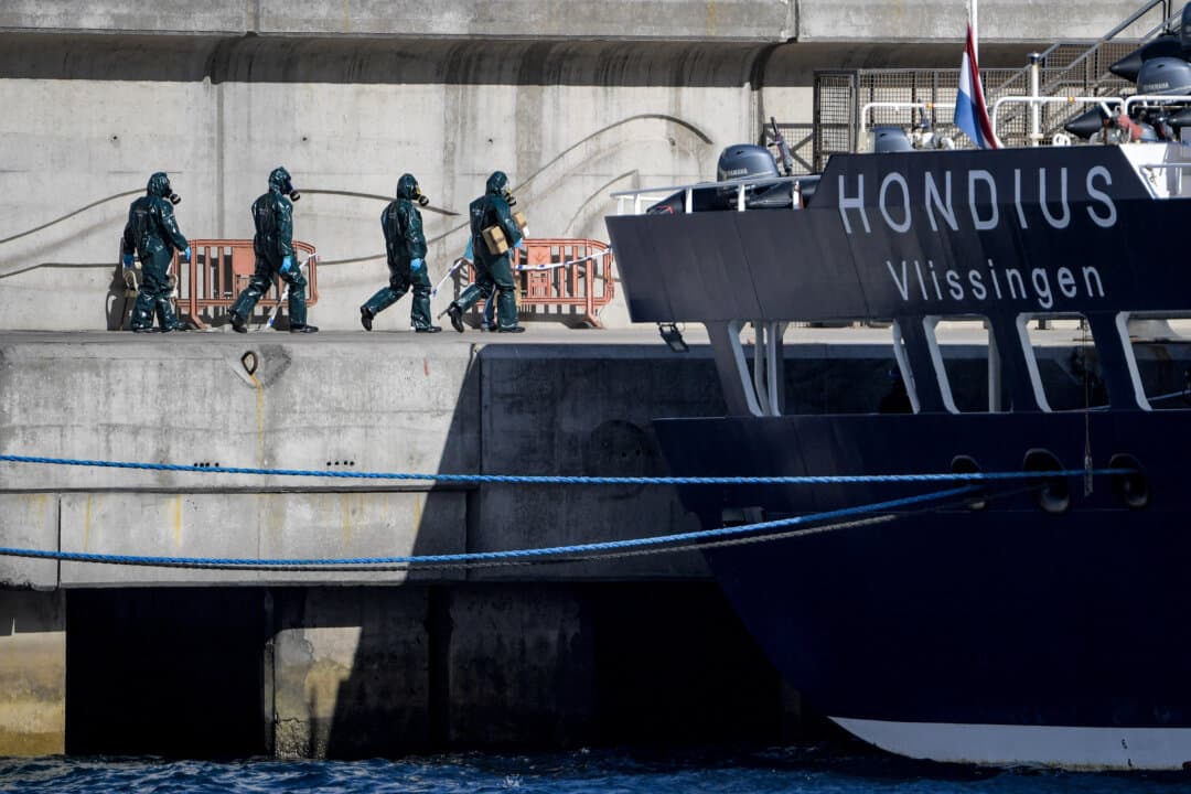 People wearing protective suits walk toward the hantavirus-stricken cruise ship MV Hondius docked in the port of Granadilla de Abona on the island of Tenerife in Spain's Canary Islands on May 11, 2026. Adverse weather conditions forced the cruise ship to dock at Tenerife before evacuations can be completed, the health ministry said. (Jorge Guerrero/AFP via Getty Images)