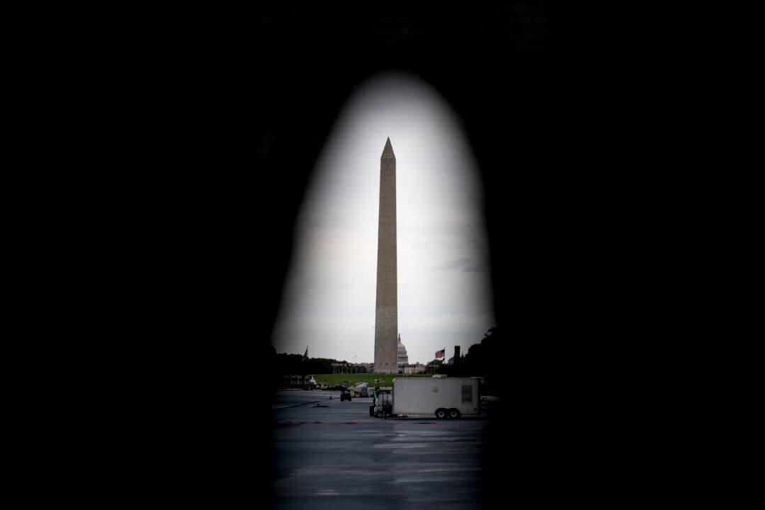 The Washington Monument is seen through a hole in the fencing at the Lincoln Memorial Reflecting Pool as it is being resurfaced in Washington on May 13, 2026. Workers have been resurfacing the bottom of Lincoln Memorial Reflecting Pool with “American flag blue”-colored material used in swimming pools, following an order by President Donald Trump. (Kent Nishimura/AFP via Getty Images)
