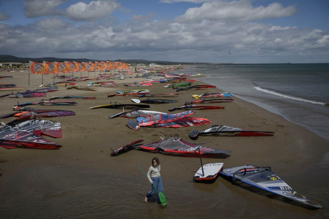 A girl walks on the beach with a fishing net during the annual Defi Wind windsurfing event in Gruissan, southern France, on May 14, 2026. The annual event draws some 1,300 competitors from around 45 countries. (Ed Jones/AFP via Getty Images)
