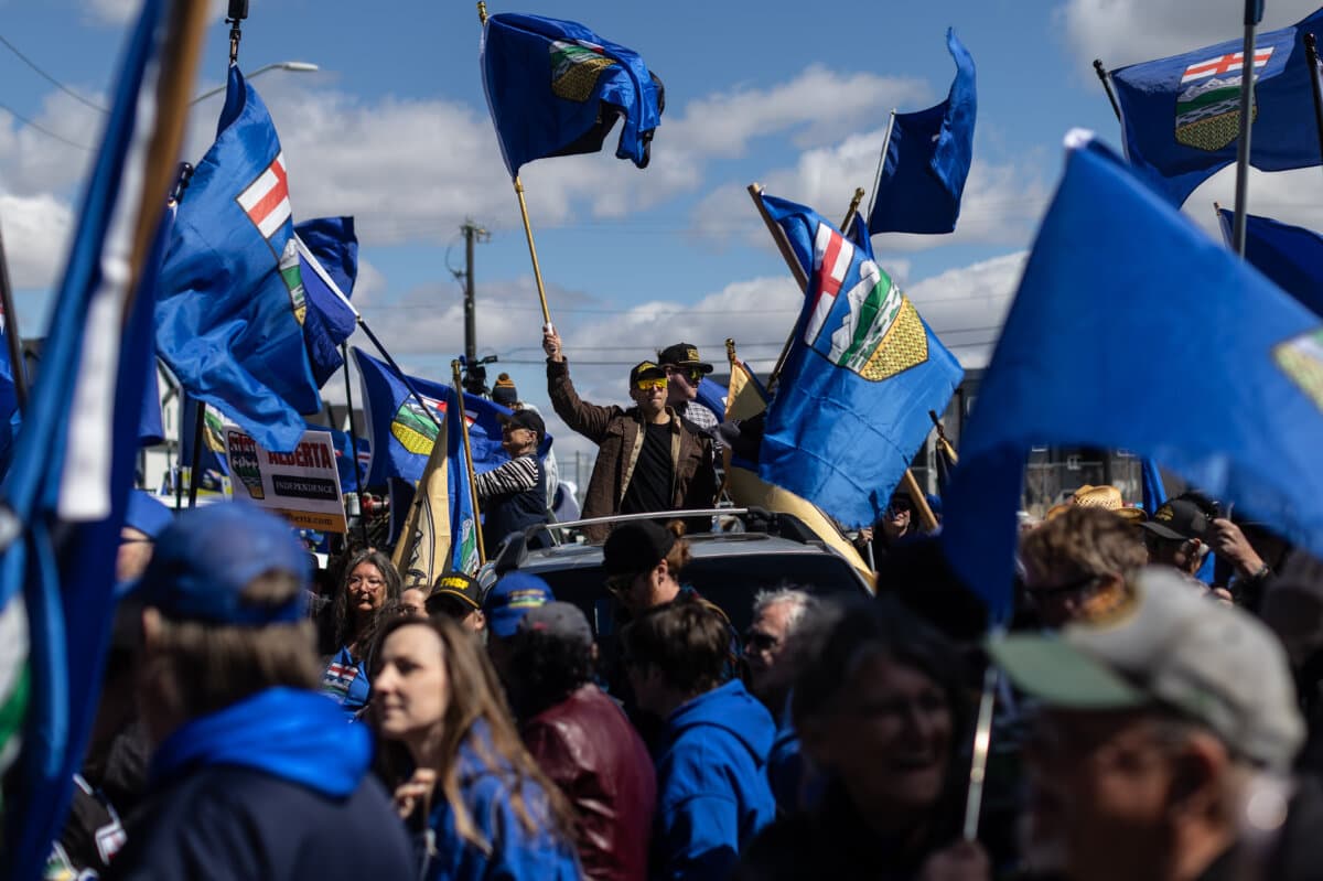Supporters wave flags in support of Mitch Sylvestre as he submits signatures for a separation referendum to Elections Alberta in Edmonton on May 4, 2026. (The Canadian Press/Jason Franson)