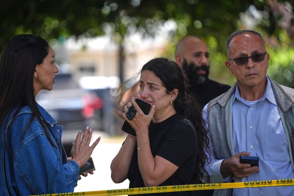 People stand behind police tape at the scene of a shooting outside the Islamic Center of San Diego on May 18, 2026. (Gregory Bull/AP Photo)