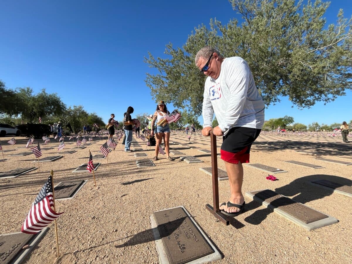 Volunteer Mike Caputo digs a small hole before placing a flag in preparation for Memorial Day at the National Memorial Cemetery in Phoenix on May 23, 2026. (Allan Stein/The Epoch Times)