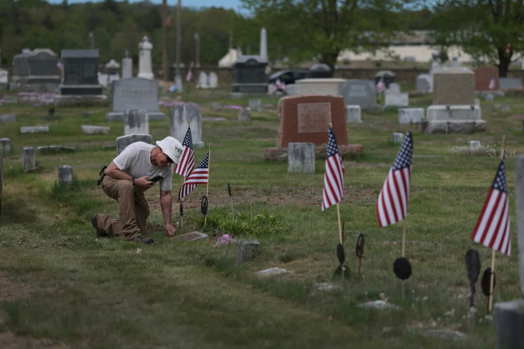 Robin Hutchinson cleans off the gravestone of his grandfather, who was a WW II veteran, at the Riverside Cemetery in Portland, Maine, on May 23, 2026. Hutchinson said he visits the grave every Memorial Day weekend. (Joe Raedle/Getty Images)