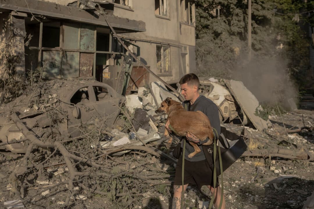 A man carries a dog in his arms among rubble outside a multi-story residential building that was damaged following a Russian missile and drone strikes on Kyiv on June 2, 2026. (Roman Pilipey/AFP via Getty Images)