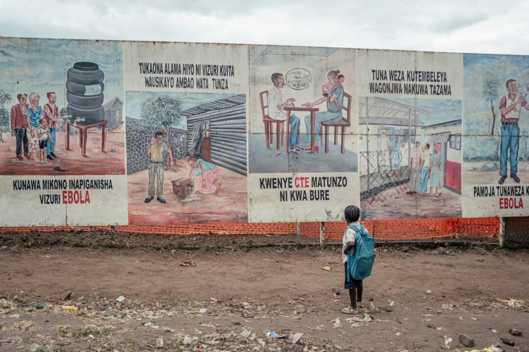 A child returning from school stops to look at Ebola awareness illustrations displayed on the signboards of the Ebola Treatment Center (ETC) in Munigi, Democratic Republic of the Congo, on June 2, 2026. (Jospin Mwisha/AFP via Getty Images)