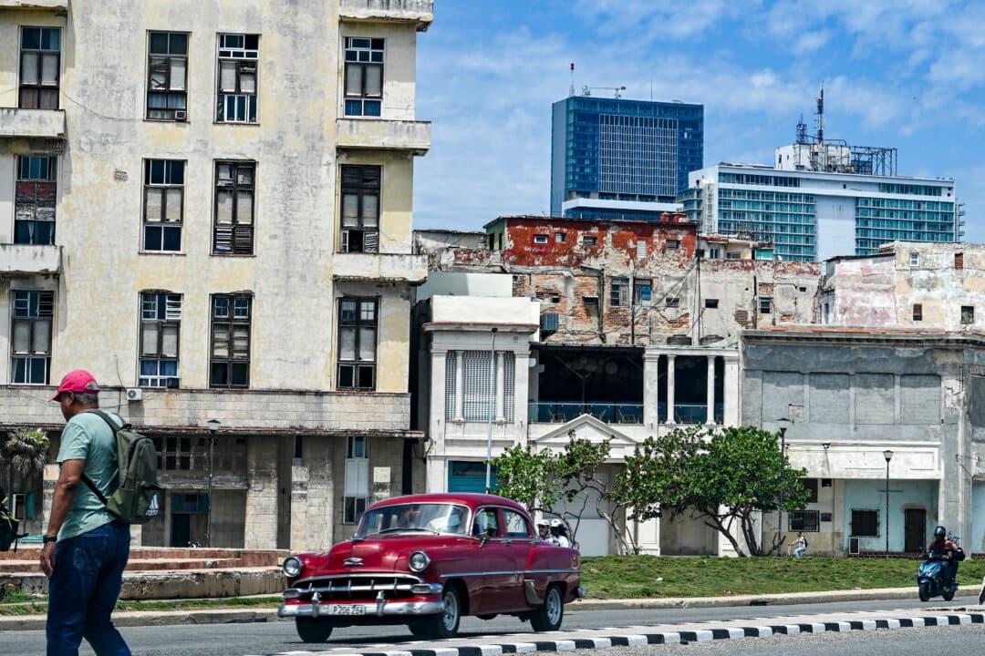 A man walks along a street as a classic car drives past, with the Iberostar Selection hotel (C) and the Habana Libre Melia hotel (R) in the background in Havana, on June 2, 2026. The Spanish hotel group Iberostar has withdrawn from managing around a dozen hotels in Cuba that it operated in partnership with the military-linked conglomerate Gaesa, which is under U.S. sanctions. (Adalberto Roque/AFP via Getty Images)