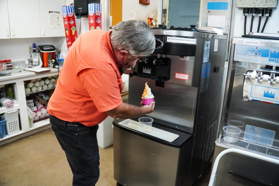 (Top) The Citrus Place, a fruit and produce market in Terra Ceia, Florida, on May 21, 2026. The store is popular among vacationers. (Bottom) Lifelong citrus farmer Sidney Tillett displays his homemade orange and vanilla swirl ice cream at The Citrus Place in Terra Ceia, Florida, on May 21, 2026. His ice cream is the store's biggest seller. (Jacob Burg/The Epoch Times)