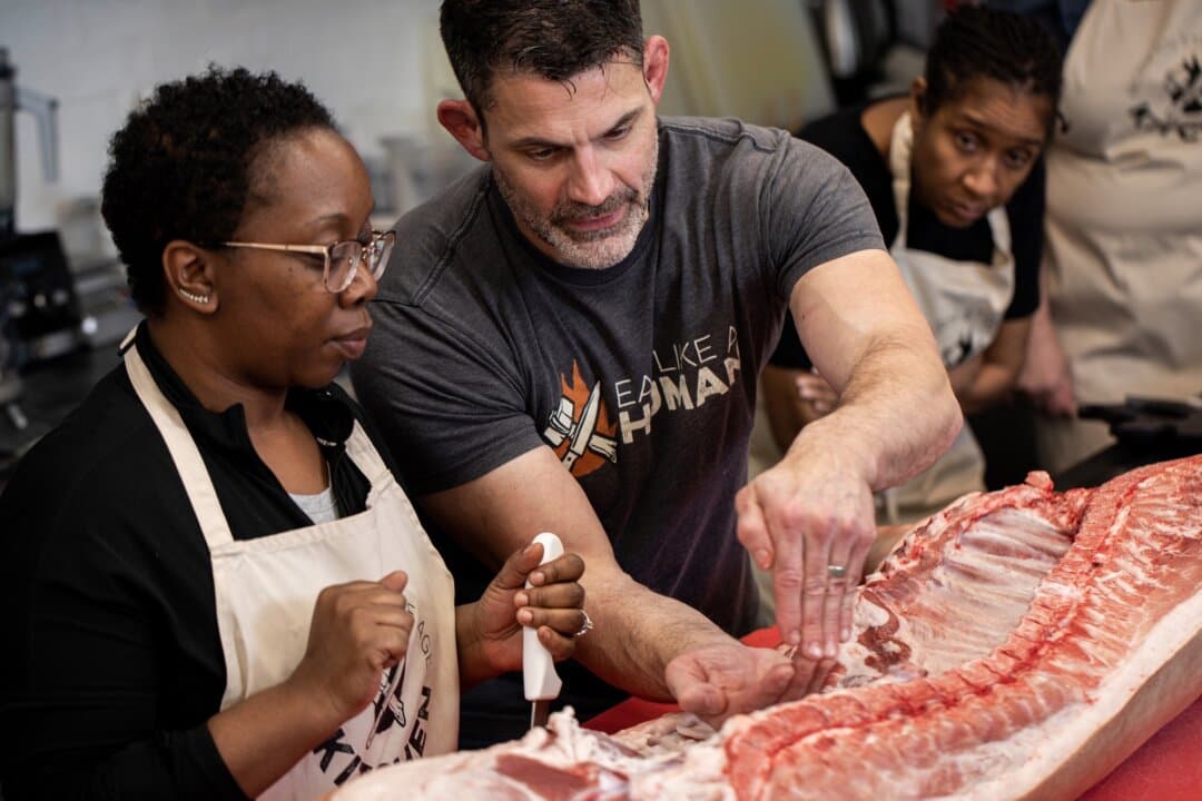Bill Schindler (center) guides a student through breaking down a pig during a nose-to-tail butchering class. (Courtesy of Jill Jasuta)