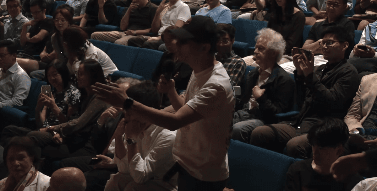 A man wearing a black hat and a white T-shirt asks a question during an event hosted by the Asia Society in New York on June 8, 2026. (Screenshot of Asia Society's video recording via The Epoch Times)