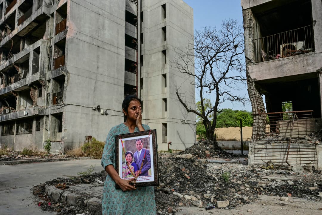 A woman holding a portrait of her relatives, who died in the Air India Flight 171 crash last year, breaks down while visiting the accident site in Ahmedabad, India, on June 11, 2026. India's aviation accident probe agency is facing renewed criticism from pilot groups ahead of the anniversary of the 2025 Air India Boeing-787 crash that killed 260 people. Victims' families had expected a final report by June 12 to explain the cause of the disaster—exactly a year after the Boeing 787-8 crashed in a fireball shortly after takeoff and smashed into a medical college. (Shammi Mehra/AFP via Getty Images)