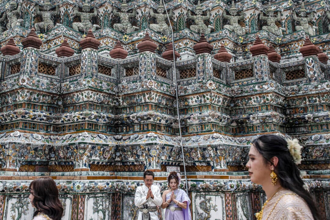 A couple (C) wearing rented traditional Thai costumes poses for photographs at Wat Arun Buddhist temple in Bangkok, on June 11, 2026. (Amaury Paul/AFP via Getty Images)