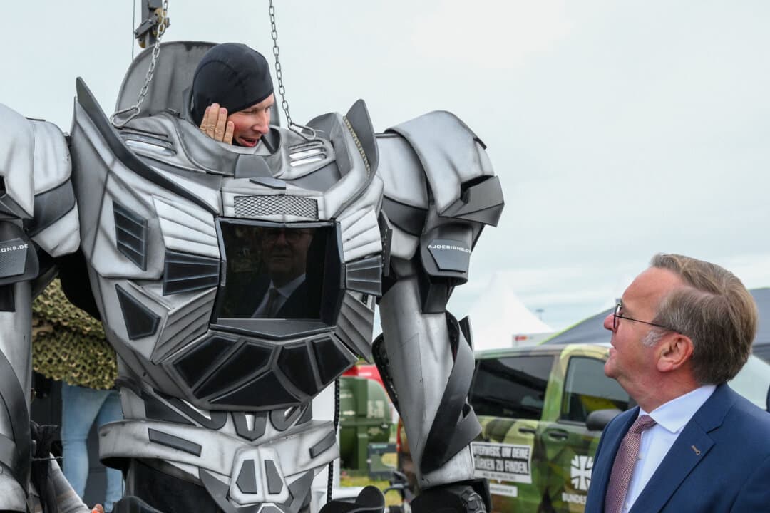 German Defense Minister Boris Pistorius greets a German soldier wearing a replica of a robot at the booth of the Bundeswehr during the International Aerospace Exhibition (ILA) at the BER Airport in Schoenefeld, Germany, on June 12, 2026. (Ralf Hirschberger/AFP via Getty Images)