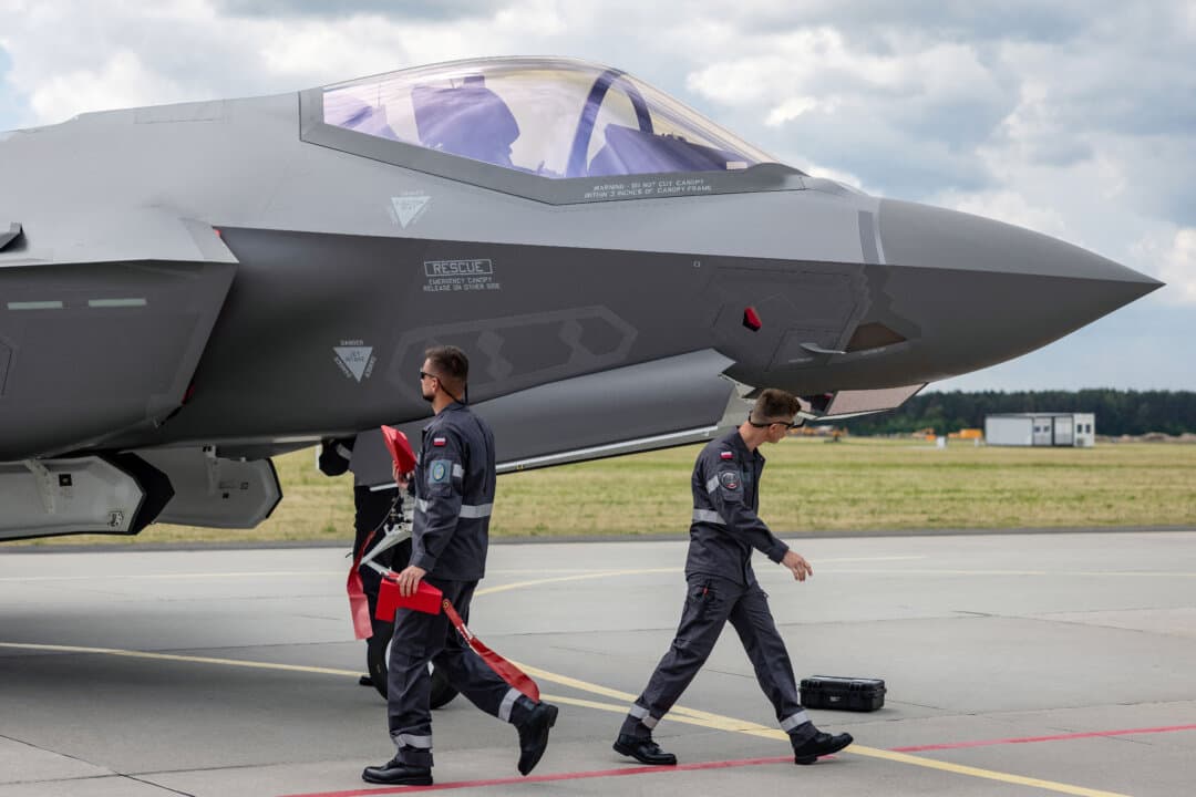 Ground crew members stand beside one of the first three U.S.-made Lockheed Martin F-35 Lightning II fighter jets, designated “Husarz” in Polish service, at the 32nd Tactical Air Base in Lask, Poland, on June 12, 2026. The aircraft officially entered service with the Polish Air Force that day. (Wojtek Radwanski/AFP via Getty Images)