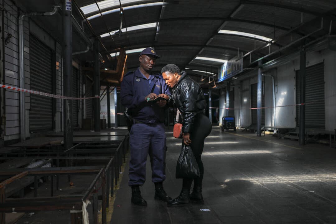 A member of the South African Police Service (SAPS) checks a woman’s passport during a joint immigration enforcement operation conducted by SAPS, the Johannesburg Metropolitan Police Department, and the Department of Home Affairs in Johannesburg on June 12, 2026. (Mzingenkosi Sibanda/AFP via Getty Images)