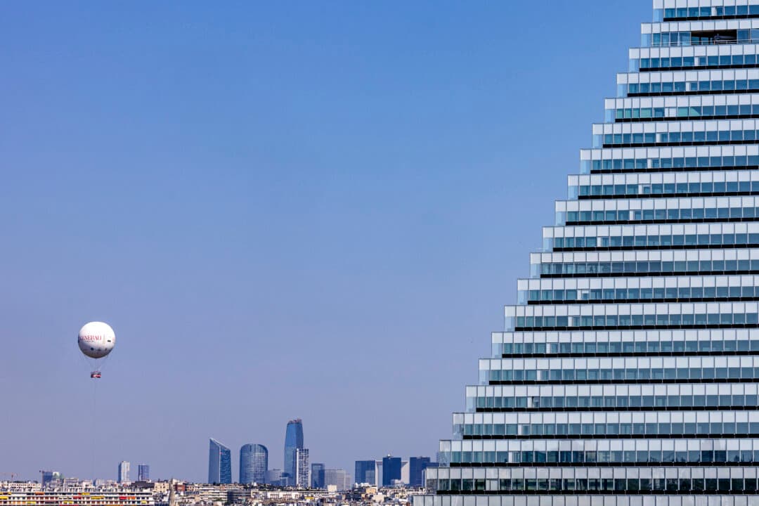 The Air Paris balloon, tasked with measuring pollution (L), is seen in front of La Defense business district (C) and the Triangle Tower on the southwestern edge in Paris, France, on June 19, 2026. (Joel Saget/AFP via Getty Images)
