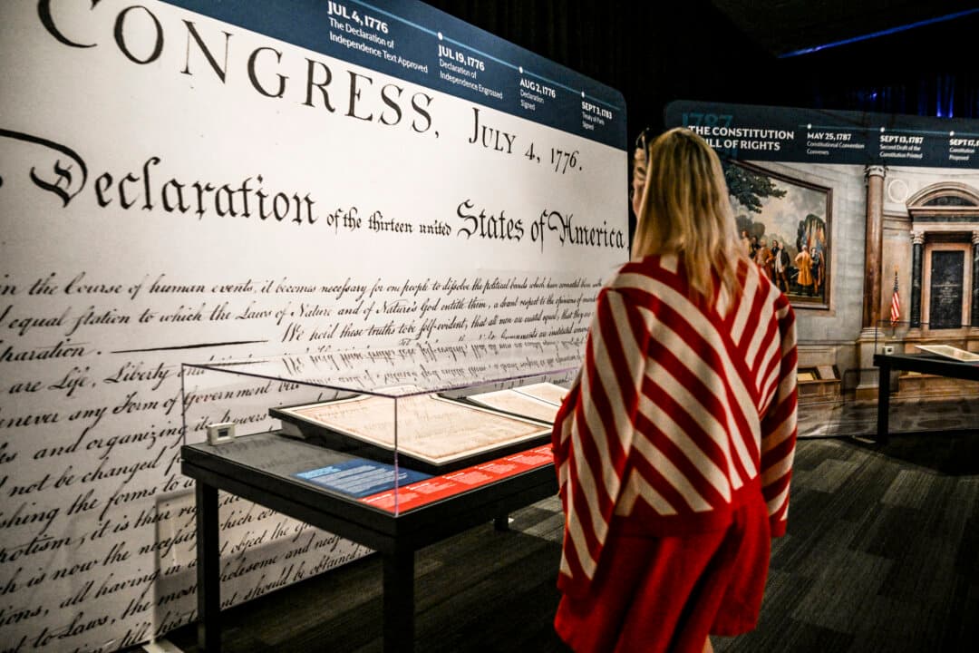 A museum staff member looks at a copy of the “Unanimous Declaration of the Thirteen United States of America” displayed during a preview of the “Freedom Plane National Tour: Documents That Forged a Nation” exhibition at the Museum of Miami in Miami, Fla., on June 18, 2026. The museum is one of eight venues selected to host the National Archives traveling exhibition marking the 250th anniversary of the United States, from June 20 to July 5, 2026. (Chandan Khanna/AFP via Getty Images)