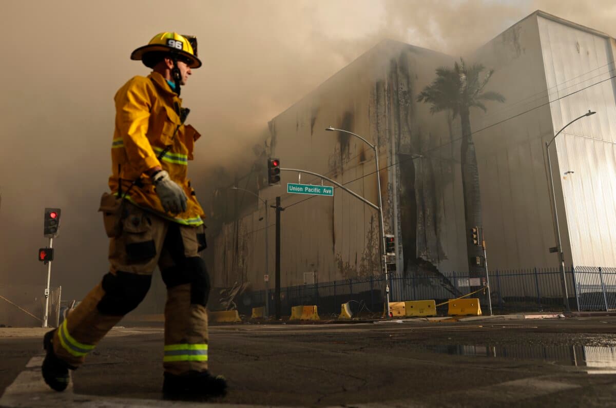 A firefighter walks down the street as a massive warehouse fire at a cold storage facility continues to burn and spread smoke around Los Angeles city on June 20, 2026. (Mario Tama/Getty Images)