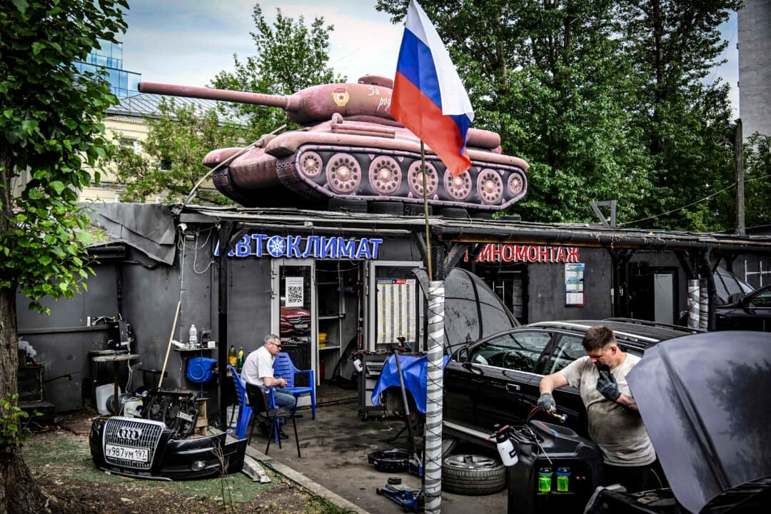 Mechanics of a small street auto service repair cars with an inflatable model of the Soviet T-34 tank on its roof in Moscow on June 22, 2026. The tank was installed for the 80th anniversary of the Soviet Union's victory over Nazi Germany in World War 2. (Alexander Nemenov/AFP via Getty Images)