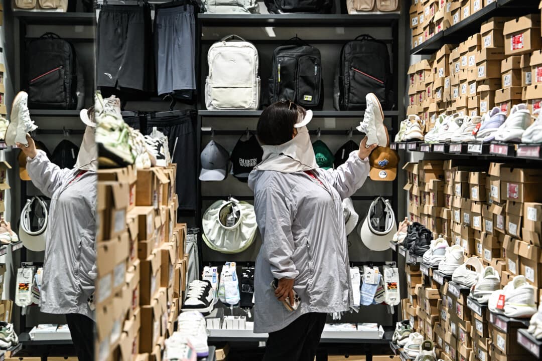 A woman checks shoes at an Anta shop that belongs to major Chinese sportswear company Anta Sports Products Limited, in Beijing on June 5, 2025. Domestic brands held 76 percent of China's consumer market in 2024, up from 66 percent in 2012, according to a survey. (Adek Berry / AFP via Getty Images)