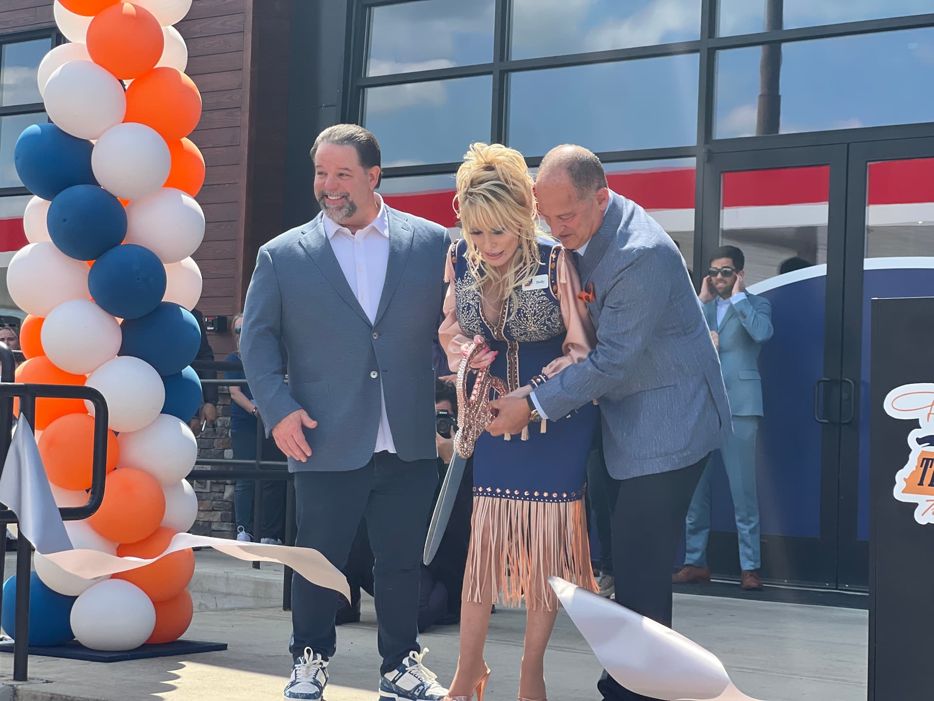 Dolly Parton and her business partner Gregory H. Sachs cut the ribbon to their new truck stop on June 24, 2026. (Jacki Thrapp/The Epoch Times)
