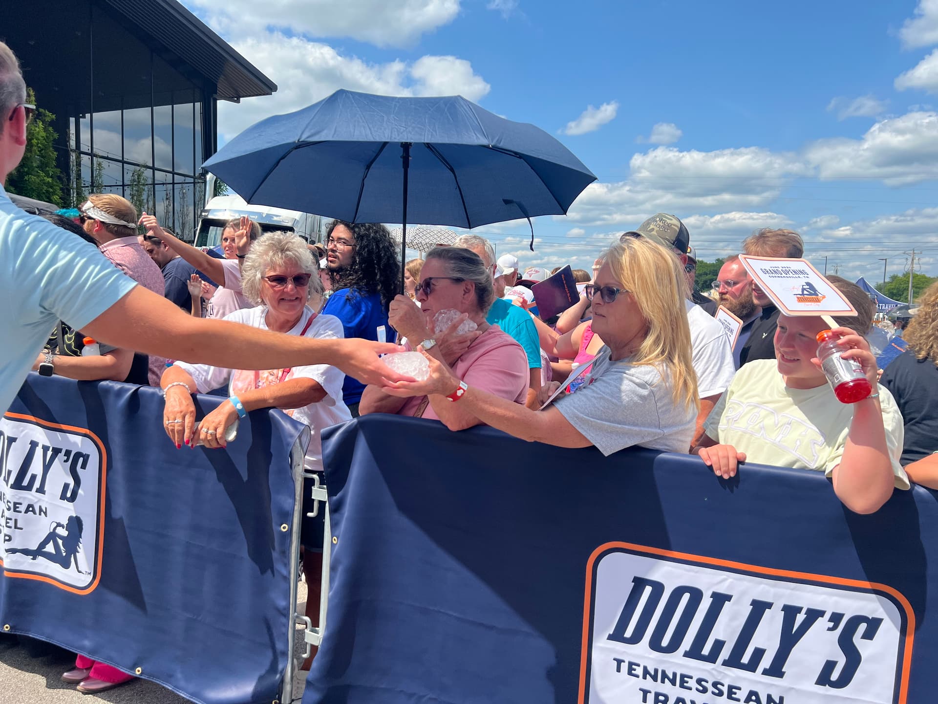 Fans were given hydrating drinks and bricks of ice to stay cool in the Tennessee heat while they waited for Dolly Parton to cut the ribbon to her first truck stop on June 24, 2026. (Jacki Thrapp/The Epoch Times)