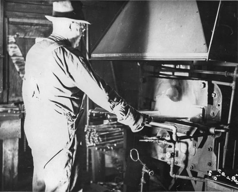 (Left) A worker carries a box of blasting caps during the construction of Mount Rushmore, near Keystone, S.D., in this file photo. During construction, powdermen cut and set dynamite charges of specific sizes to remove precise amounts of rock to carve the presidents' facial features. (Right) A blacksmith works during the construction of Mount Rushmore, near Keystone, S.D., in this file photo. Blacksmiths sharpened hundreds of drill bits each day. (Courtesy of South Dakota Historical Society)