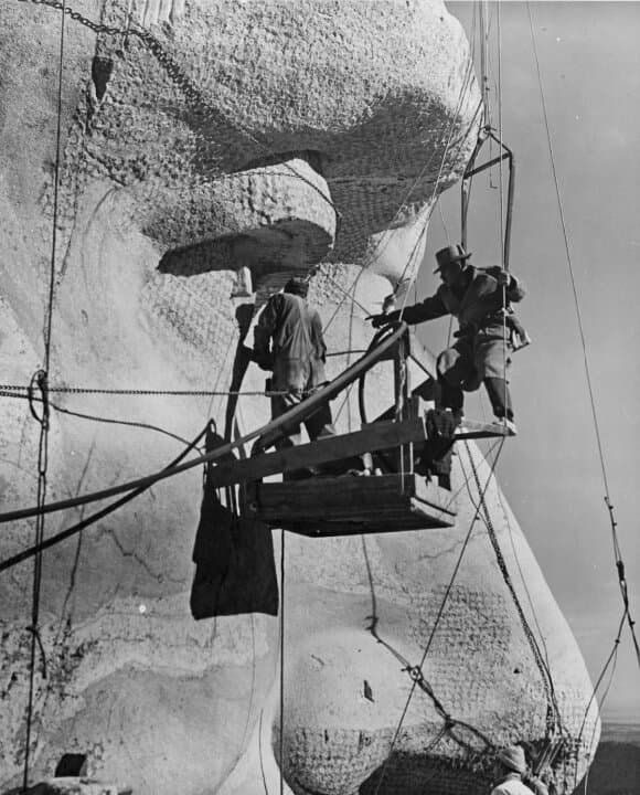 (Top Left) Gutzon Borglum and his crew work on the face of Abraham Lincoln near Keystone, S.D., in this file photo. Borglum originally intended the sculptures to include the presidents' torsos. (Top Right) Borglum and site manager Jesse Tucker during Mount Rushmore construction, near Keystone, S.D., in this file photo. (Bottom Left) Sculptor Gutzon Borglum and his son, Lincoln Borglum, on Mount Rushmore, in this file photo. Lincoln Borglum oversaw the completion of Mount Rushmore after his father's death. (Bottom Right) Gutzon Borglum provides guidance to workers on the Mount Rushmore project, near Keystone, S.D., in this file photo. (Courtesy of South Dakota Historical Society)
