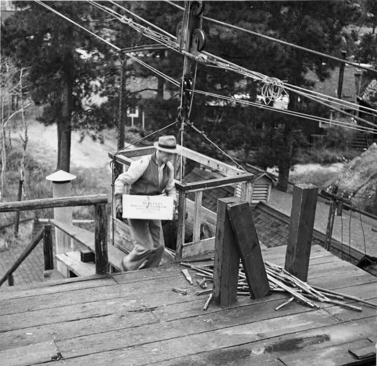 (Left) A worker carries a box of blasting caps during the construction of Mount Rushmore, near Keystone, S.D., in this file photo. During construction, powdermen cut and set dynamite charges of specific sizes to remove precise amounts of rock to carve the presidents' facial features. (Right) A blacksmith works during the construction of Mount Rushmore, near Keystone, S.D., in this file photo. Blacksmiths sharpened hundreds of drill bits each day. (Courtesy of South Dakota Historical Society)