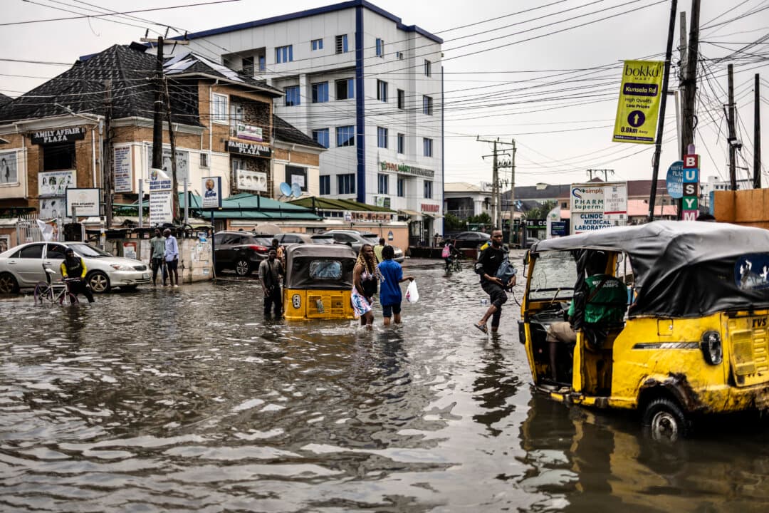 Pedestrians wade through a flooded street in Lekki neighborhood in Lagos, Nigeria, on July 3, 2026. (Olympia de Maismont/AFP via Getty Images)