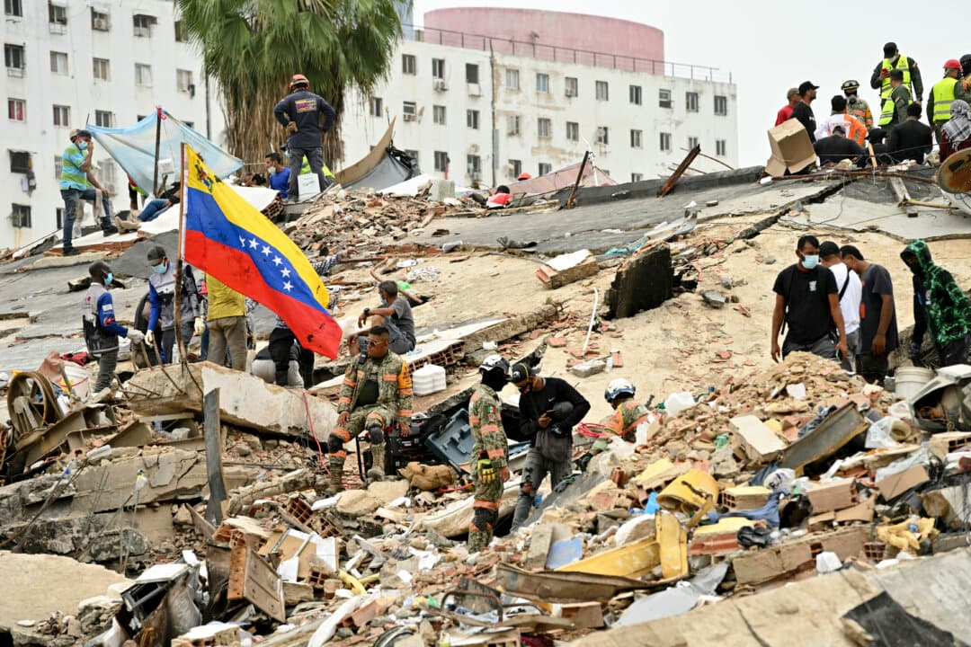 Rescuers and volunteers work amid the rubble of collapsed buildings, as a Venezuelan flag is raised, in Caraballeda, La Guaira state, Venezuela, on July 3, 2026. (Martin Beretti/AFP via Getty Images)