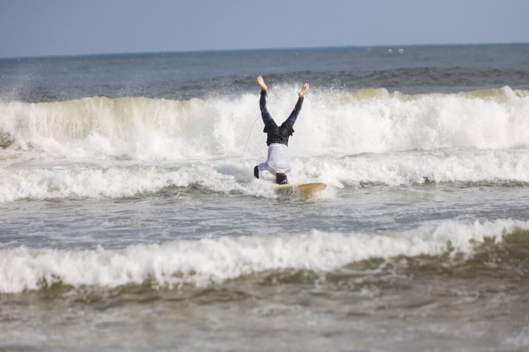 A Palestinian youth does a headstand on a surfboard while riding a wave in the Mediterranean Sea off Gaza City on July 4, 2026. (Ahmed Al Arini/Middle East Images/AFP via Getty Images)
