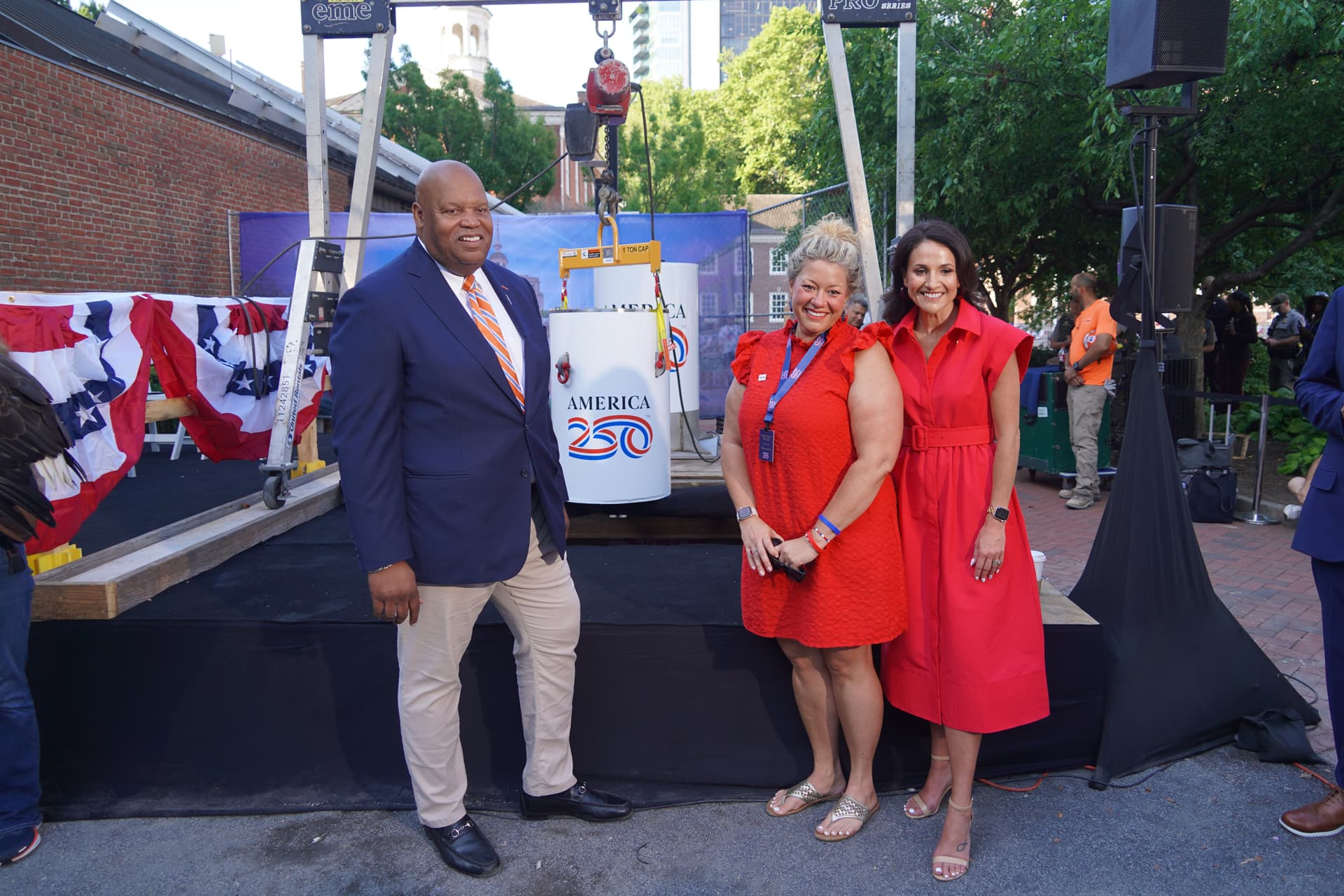 Reginald Browne, a commissioner of the U.S. Semiquincentennial Commission (L), and Jennifer Condon, executive vice president of America250.org (R), pose with attendees in front of the time capsule at Independence Hall in Philadelphia on July 4, 2026. (William Huang /The Epoch Times)