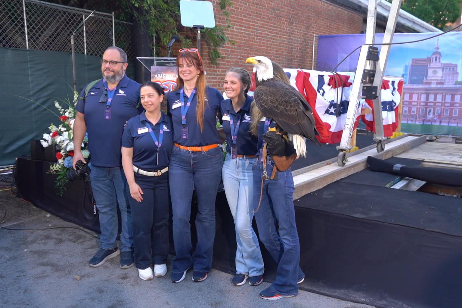 On July 4, 2026, a ceremony marking the United States’ 250th anniversary was held on the lawn at Independence Hall. The photo shows attendees posing with a bald eagle. (William Huang /The Epoch Times)