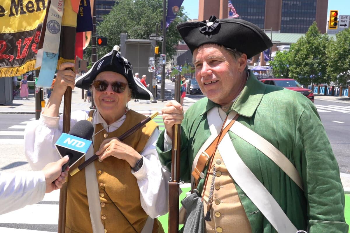 Roseanne and Philip Swain of Massachusetts, dressed in authentic 1775 Massachusetts militia uniforms, performed at the Independence National Historical Park in Philadelphia on July 3, 2026. (Nancy Wang/The Epoch Times)