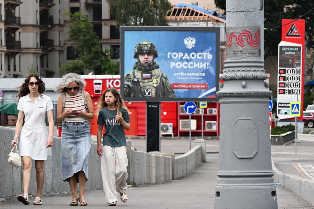People pass a billboard honoring a participant in Russia's military campaign in Ukraine and a Neftmagistral gas station sign showing no gasoline is available in Moscow on July 10, 2026. Fuel shortages have emerged across parts of the country following Ukrainian strikes on Russian refineries, fuel depots, and logistics infrastructure. (Igor Ivanko/AFP via Getty Images)