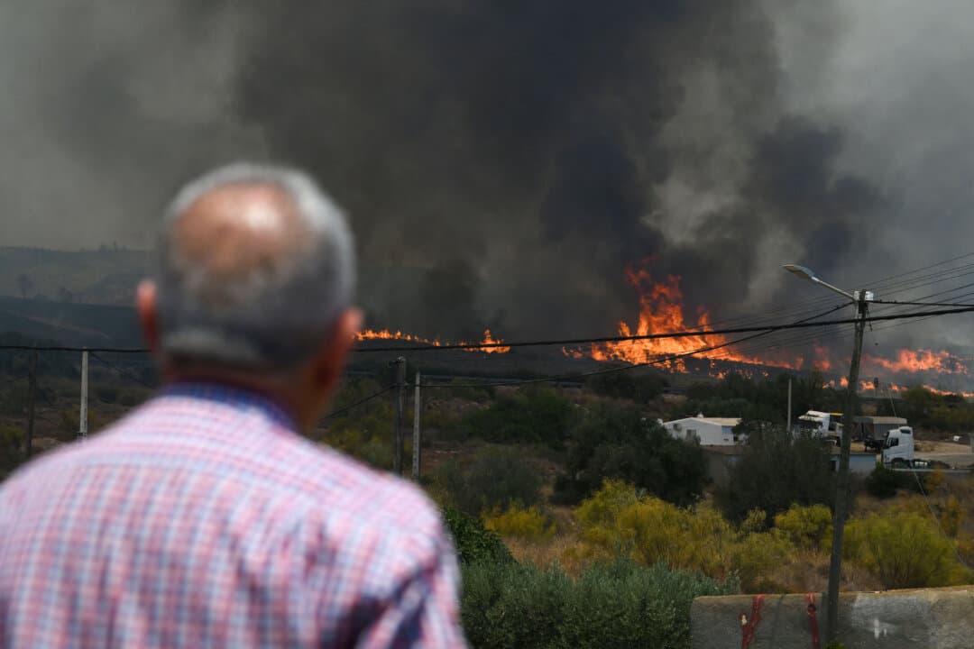 A man watches flames approach homes during a wildfire near Bedar in Los Gallardos district of Almeria Province, Spain, on July 10, 2026. The wildfire killed 11 people and left 19 others missing, according to authorities. (Jose Jordan/AFP via Getty Images)