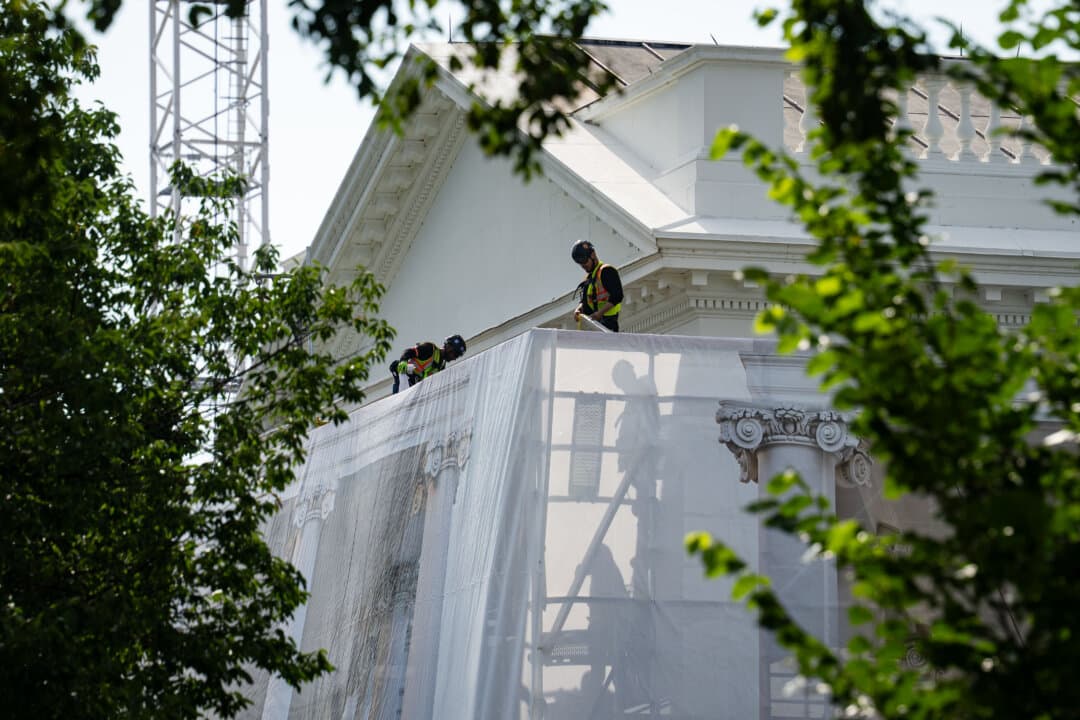 Construction workers place a tarp over the scaffolding that surrounds the columns at the North Portico of the White House on July 10, 2026. (Al Drago/Getty Images)
