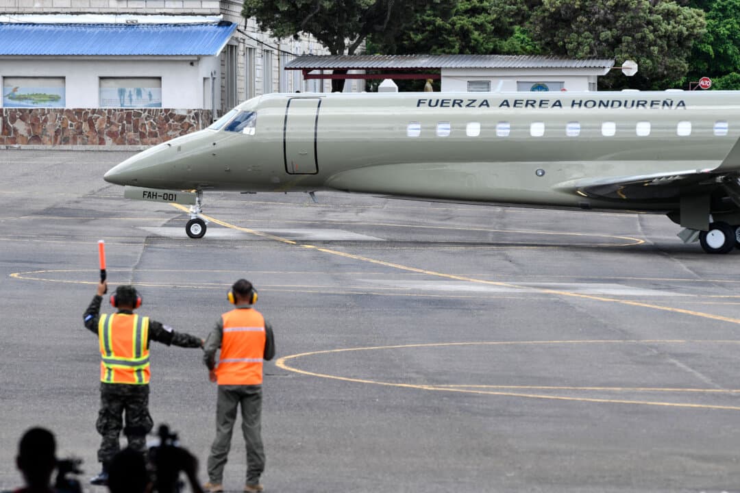 Workers stand beside the former Honduran presidential aircraft after it was auctioned as part of government austerity measures at Hernán Acosta Mejía Air Base in Tegucigalpa, Honduras, on July 10, 2026. The Embraer Legacy 600 jet, acquired during the administration of former President Juan Orlando Hernández, was sold to the Mexico-based engineering and consultancy firm THEBE. (Orlando Sierra/AFP via Getty Images)