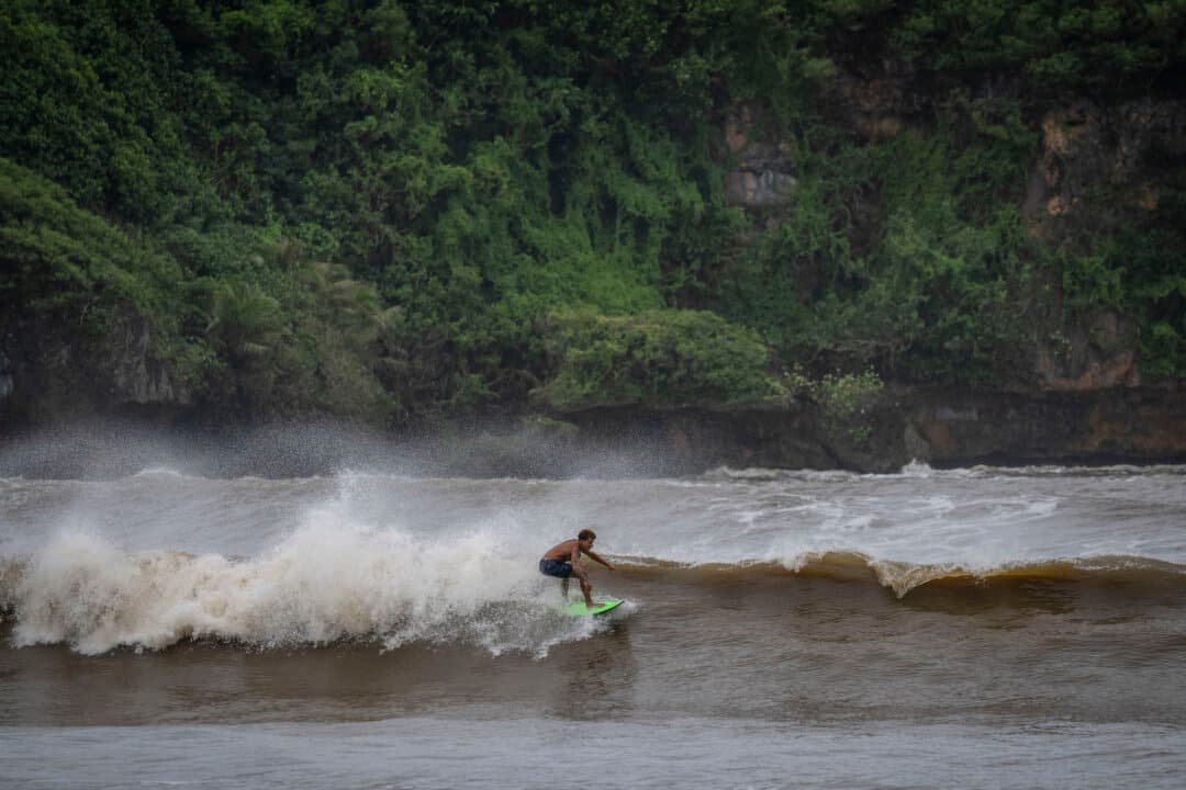 A surfer rides a high wave due to the effects of Super Typhoon Bavi in Guam on July 5, 2026. People in Guam and the Northern Marianas moved to emergency evacuation centers and made last-minute preparations on July 5. (Yuichi Yamazaki/AFP via Getty Images)