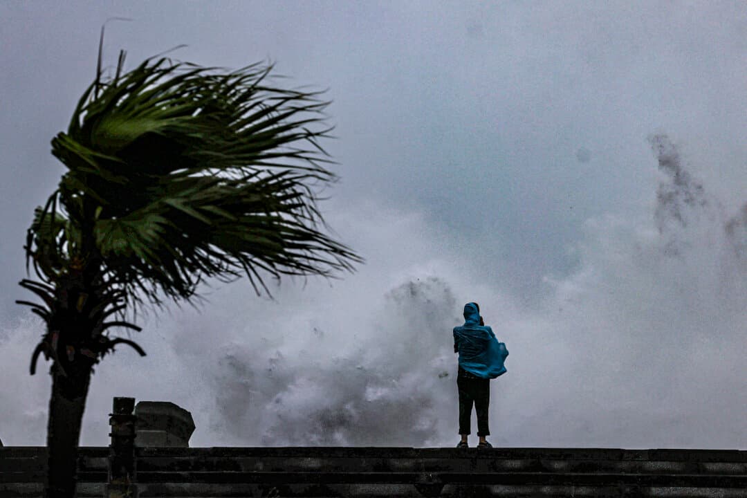 A person looks on as large waves crash against the coast as Typhoon Bavi passes off Taiwan, in Keelung, on July 11, 2026. (I-Hwa Cheng/AFP via Getty Images)