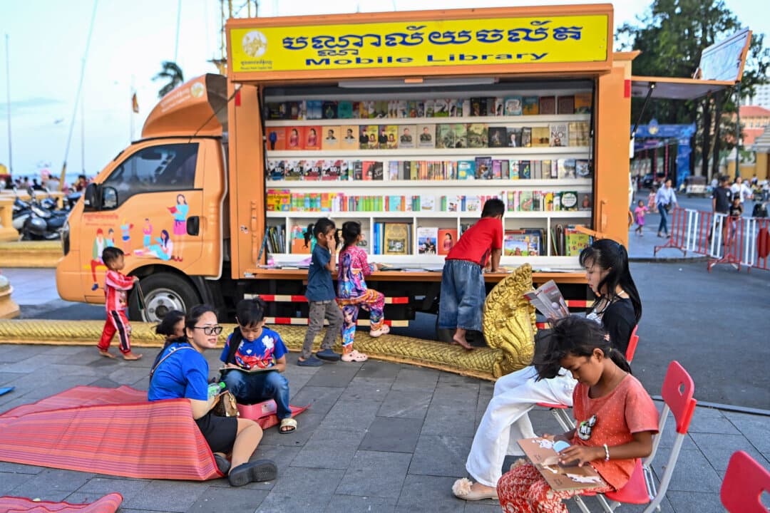 People read books at a mobile library in front of the Royal Palace in Phnom Penh, Cambodia, on July 11, 2026. (Tang Chhin Sothy/AFP via Getty Images)