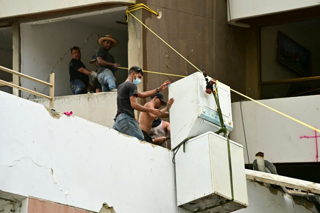 People salvage a washer-dryer from a damaged residential building in Caraballeda, La Guaira state, Venezuela, on July 11, 2026, following twin earthquakes that struck the region. (Martin Bernetti/AFP via Getty Images)