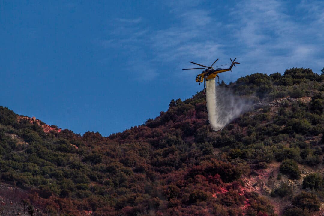A helicopter drops water to combat a hotspot as the Summit Fire continues to burn in the hills in Llano, Calif., on July 11, 2026. The fire has charred at least 2,690 acres. (Apu Gomes/Getty Images)